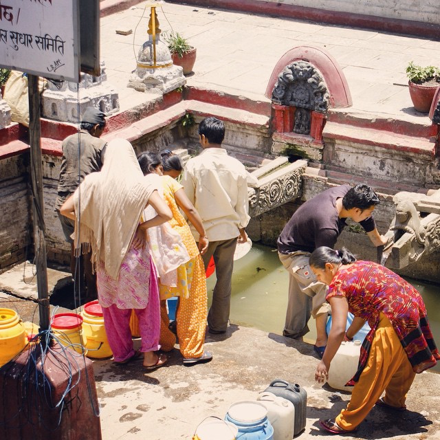 People with water containers collect and wait for water at Tanga Hiti, a stone spout in Patan, Kathmandu Valley.